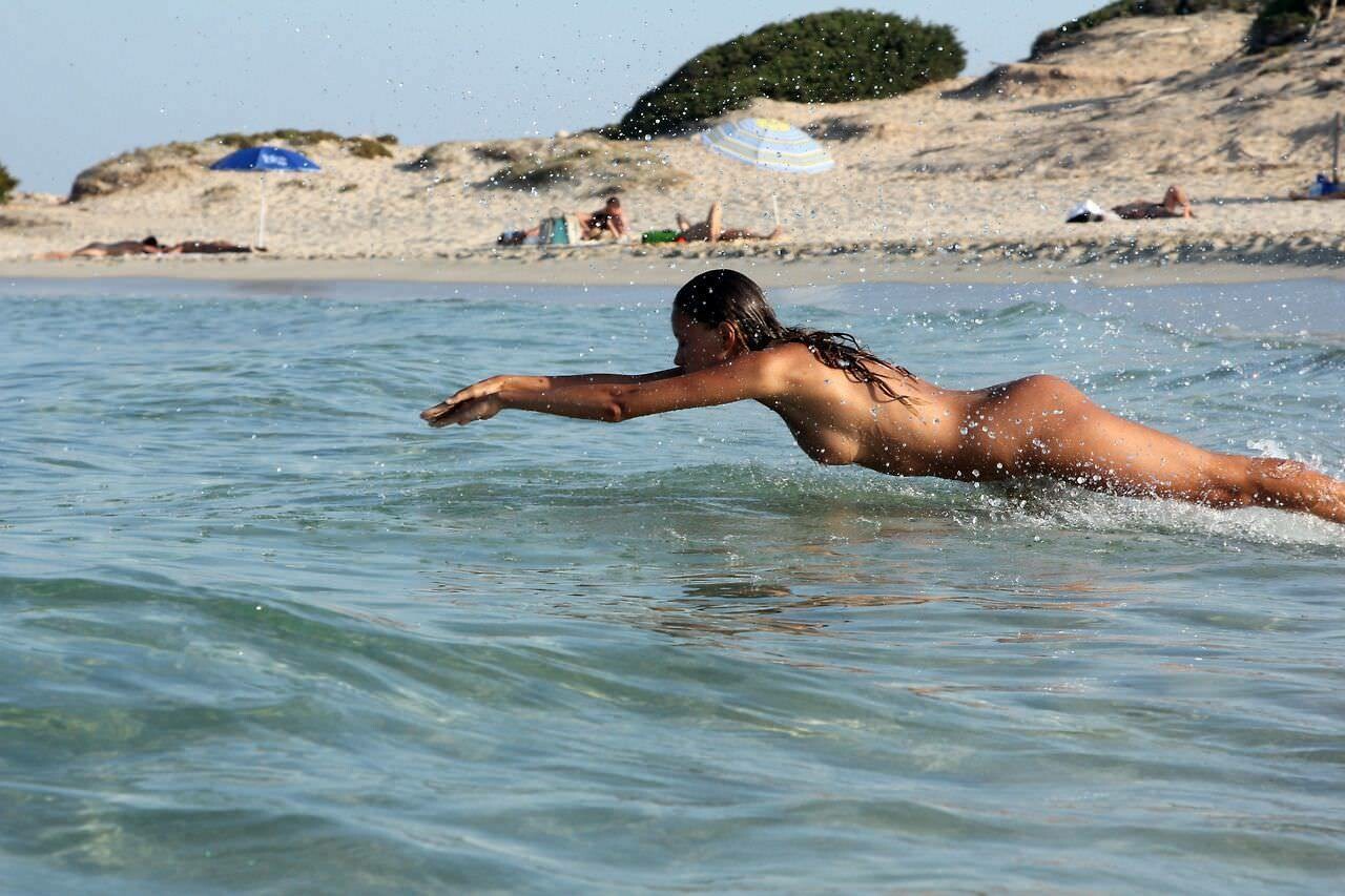 Молодая нудистка загорает на солнечном пляже