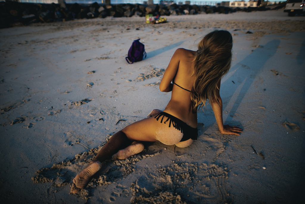 Стройная нудистка гуляет по пляжу вечером и валяется на песке
